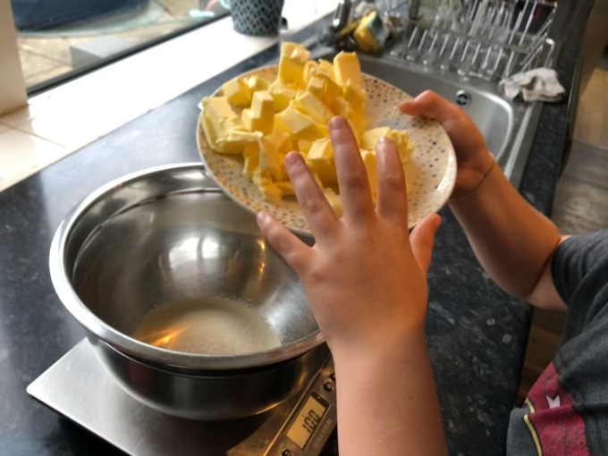 adding butter to sugar