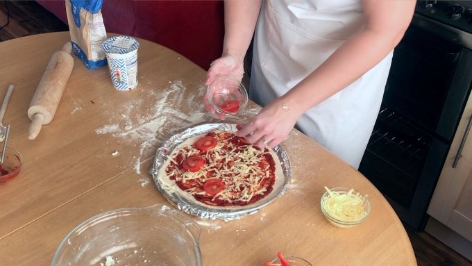 adding toppings to easy pizza dough